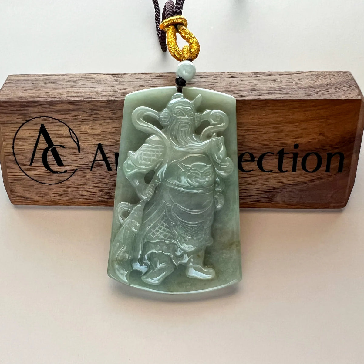 Front view of polished jade pendant hanging on display stand