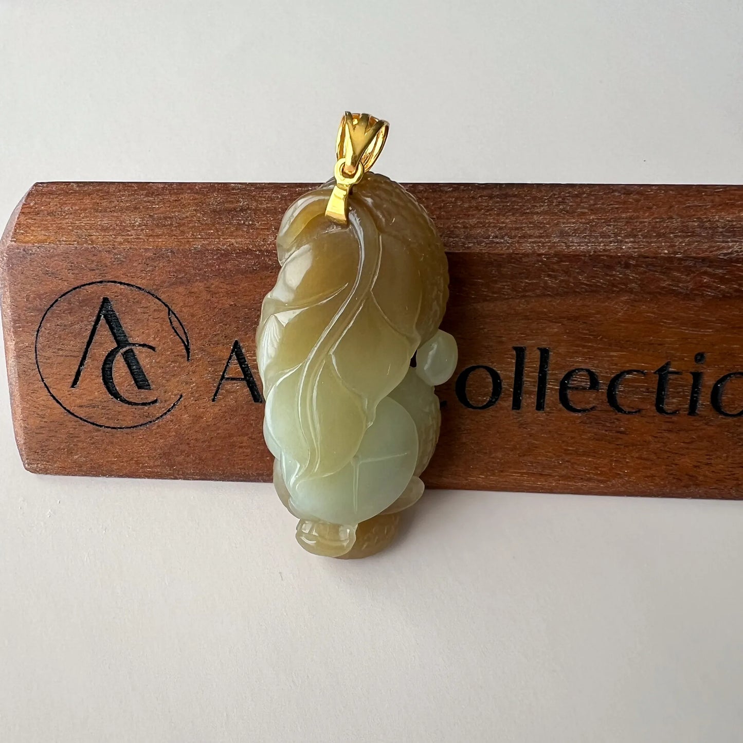Back view of yellow-green Natural Jade pendant showing leaf carving, gold-tone bail, and polished surface
