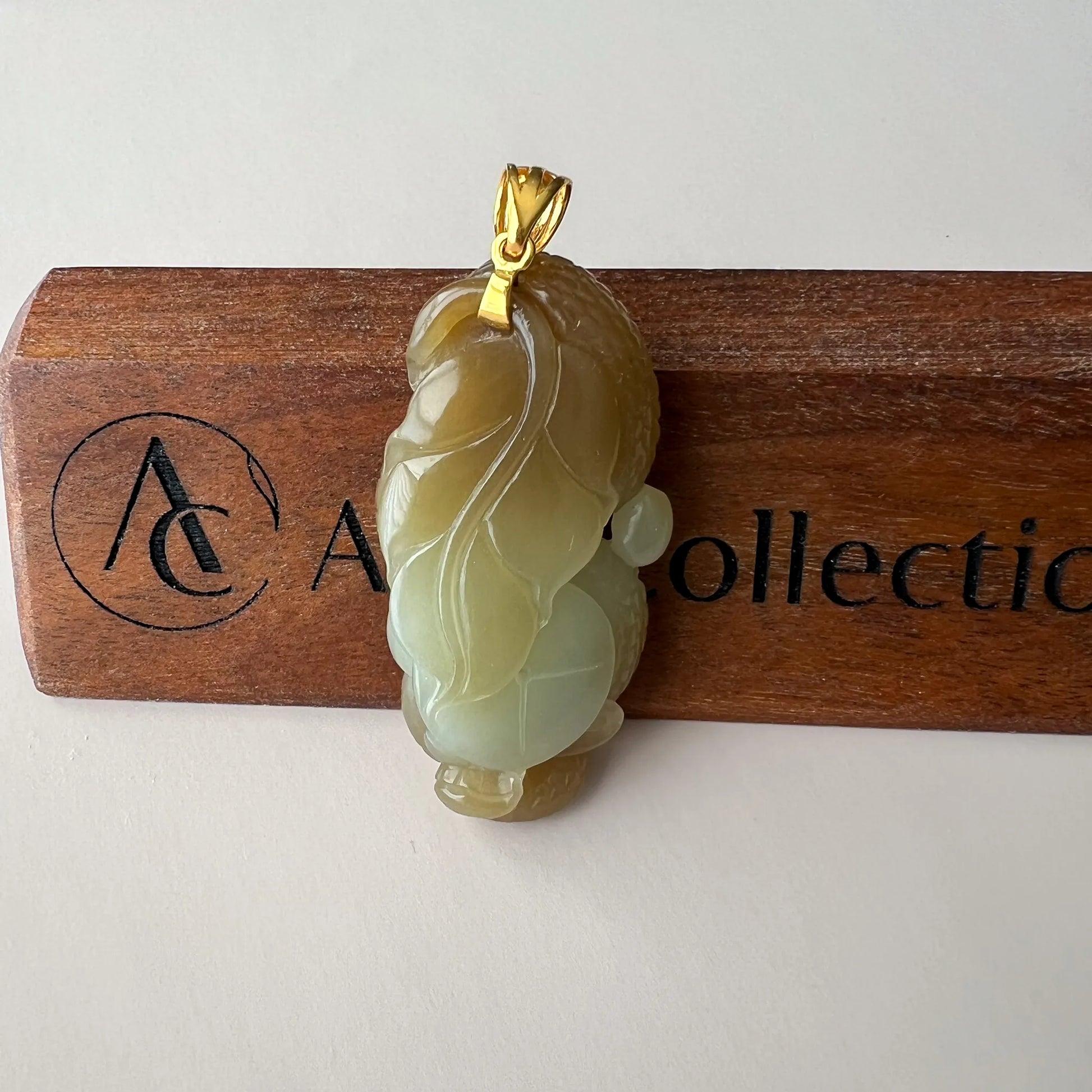 Back view of yellow-green Natural Jade pendant showing leaf carving, gold-tone bail, and polished surface