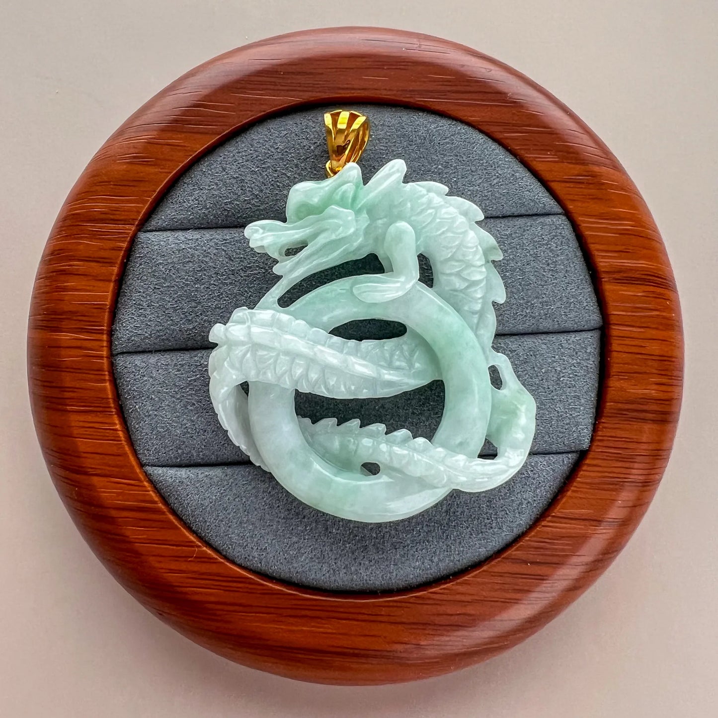 Rear view of jade dragon pendant in round wood display case with polished finish
