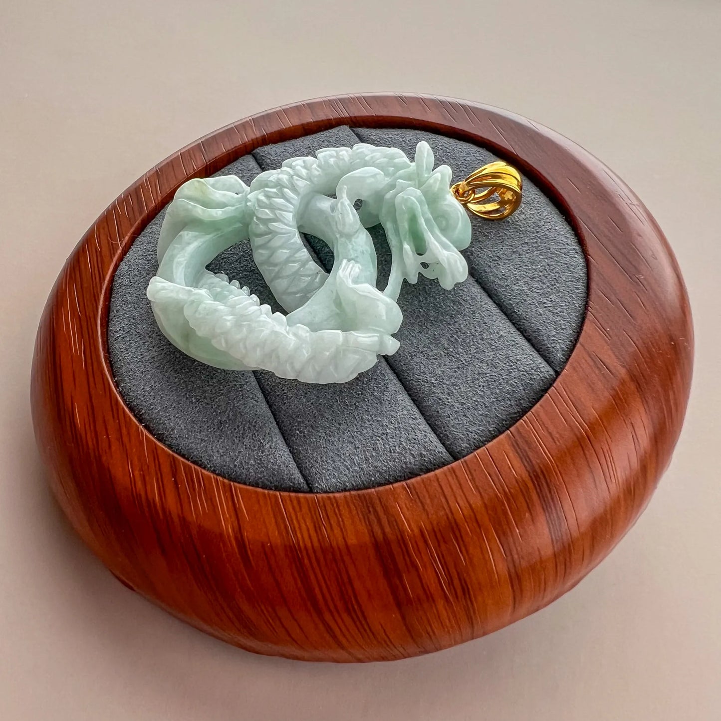 Three-quarter view of carved jade dragon pendant with glossy light green stone finish