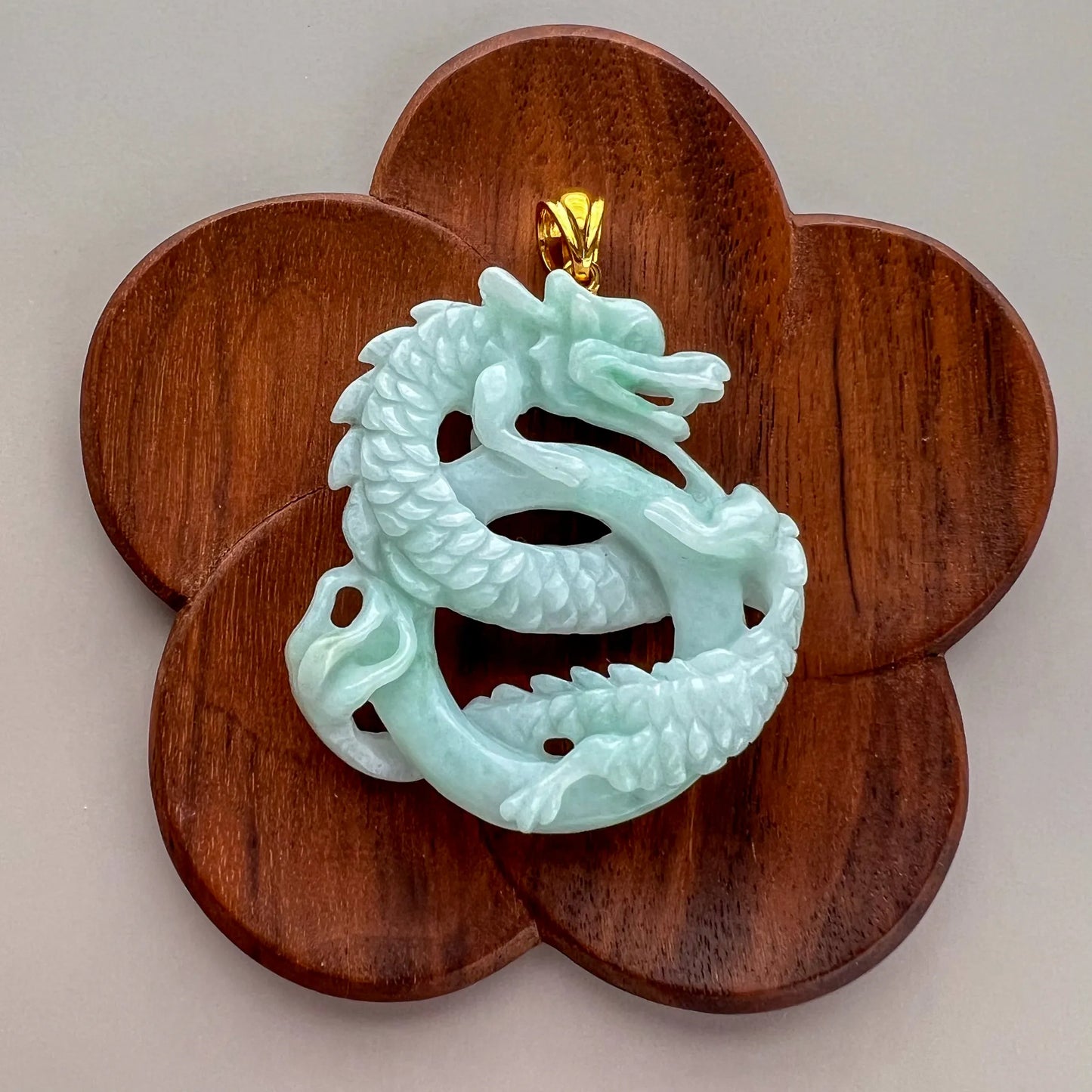 Front view of jade dragon pendant on flower-shaped wooden display stand