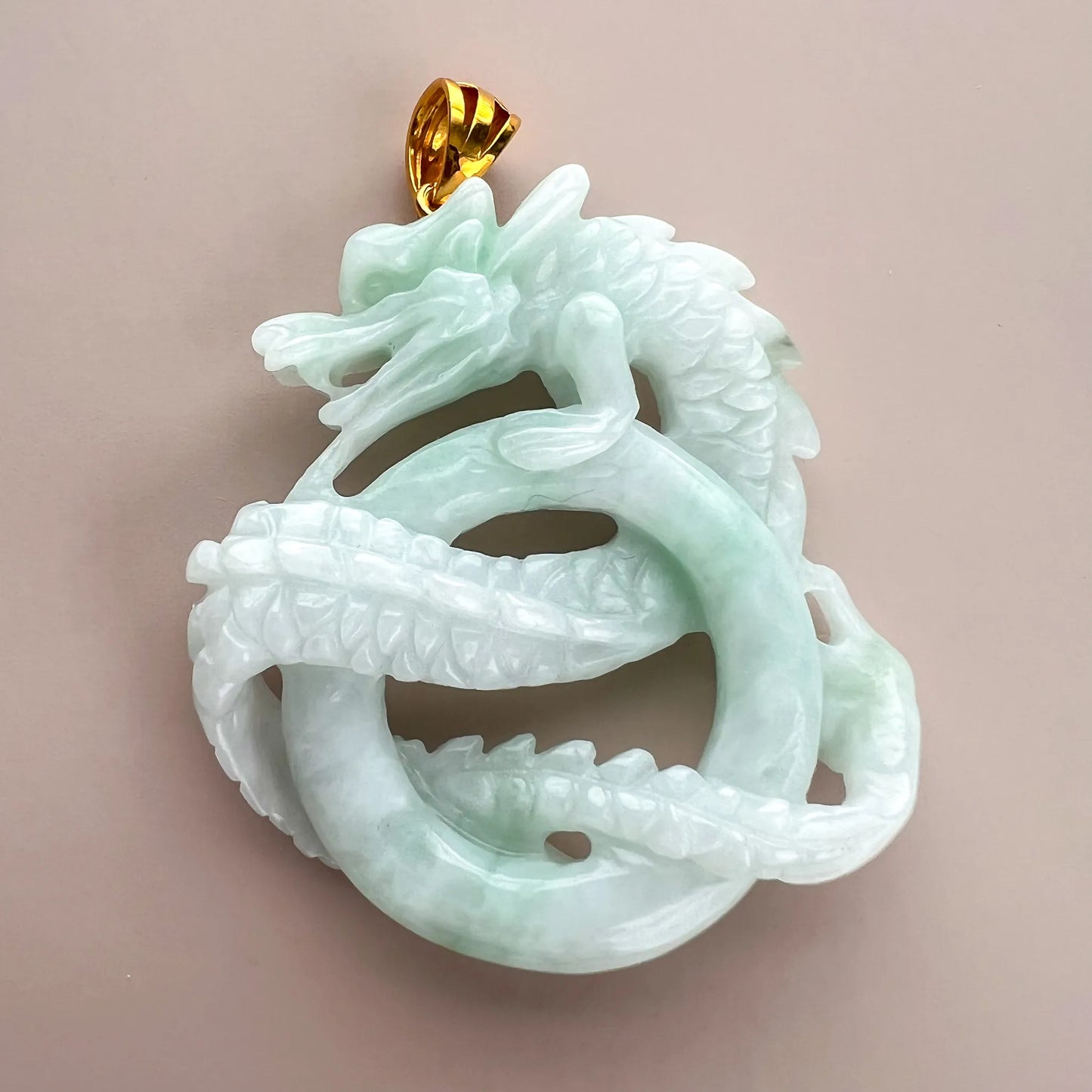 Back view of pale green natural jade double dragon carving with polished finish and gold-tone bail
