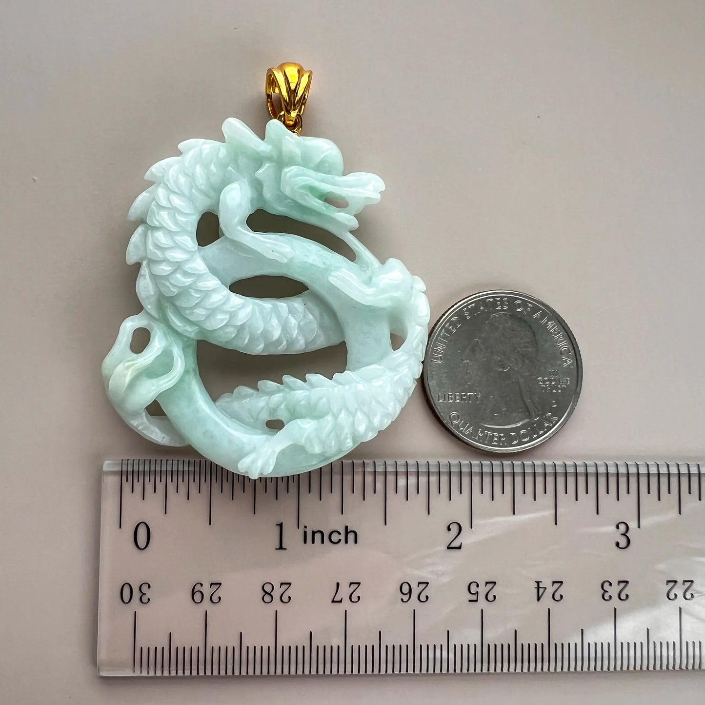 Jade dragon pendant shown with ruler and coin for size reference