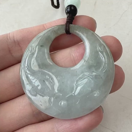 Video of hand-carved pale green and creamy gray jade pendant with two fish in a circular openwork design
