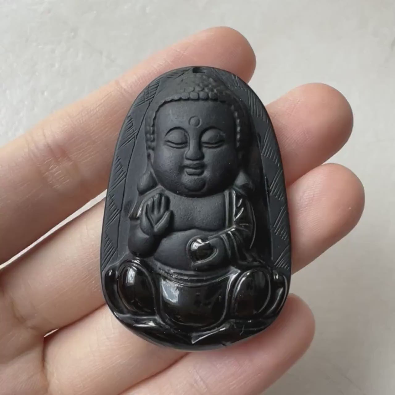 Video of a hand-carved Baby Buddha pendant with matte and glossy dual-polish finish, serene pose, and refined detail