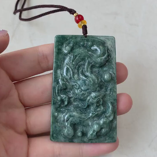 Video of hand-carved natural jadeite jade dragon pendant in green, with intricate scales, claws, and expressive face