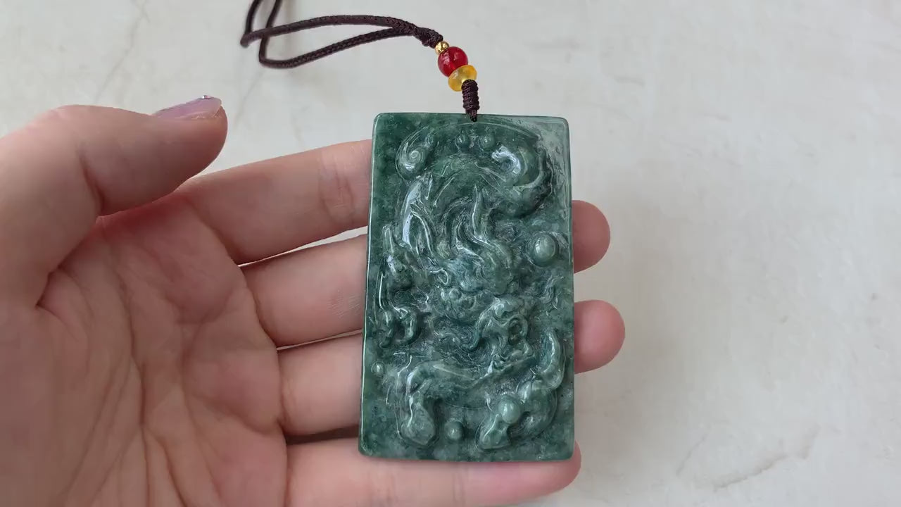 Video of hand-carved natural jadeite jade dragon pendant in green, with intricate scales, claws, and expressive face