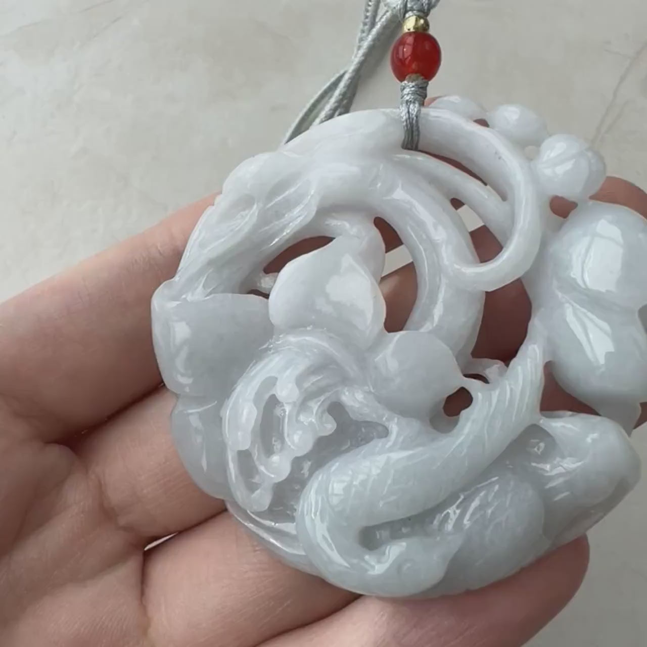 Video of hand-carved natural jadeite jade pendant with openwork floral pattern and two detailed birds, elegant green design