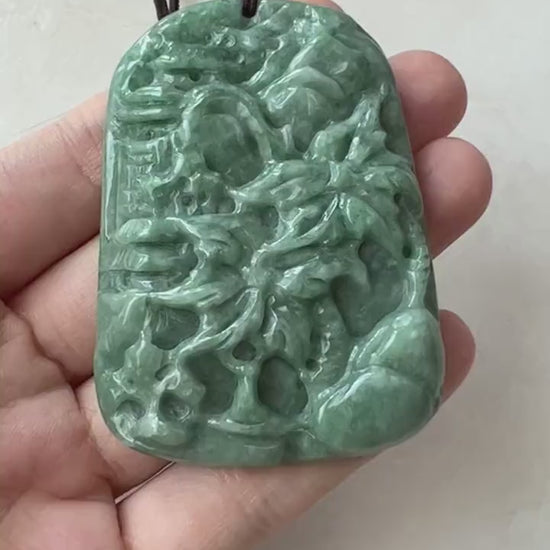 Video of hand-carved green jade pendant with tropical mountain, palm tree, and forest landscape design