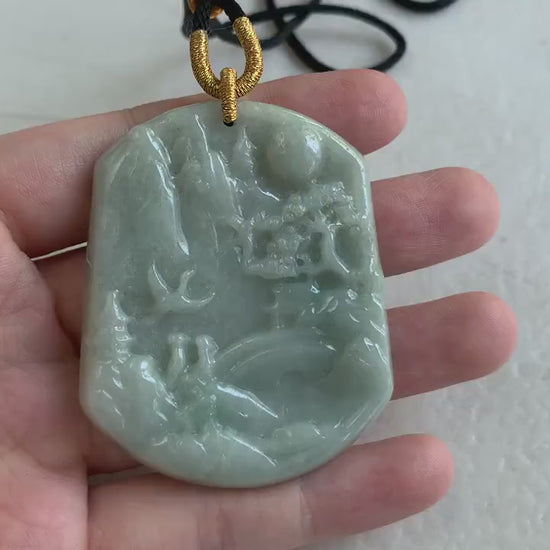 Video of a hand-carved jade pendant in tranquil green tones with a detailed mountain and forest landscape design