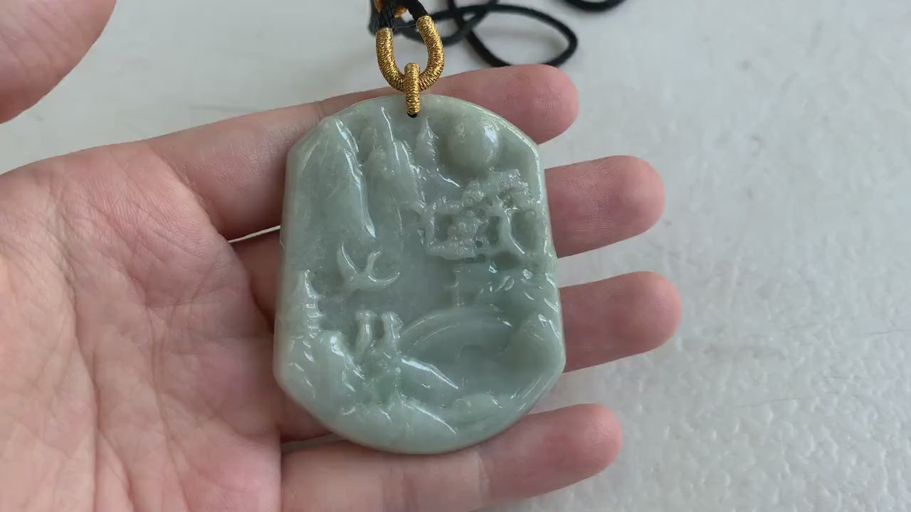 Video of a hand-carved jade pendant in tranquil green tones with a detailed mountain and forest landscape design