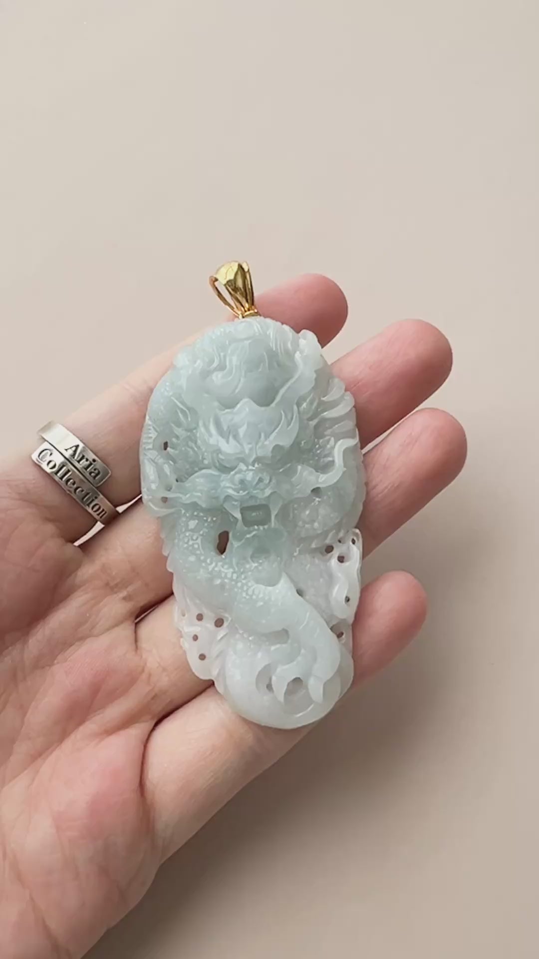 Video of an icy pale blue jadeite dragon pendant with openwork relief and 18k gold bail, polished and translucent