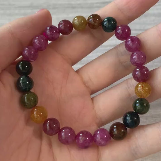 Video of an elastic natural tourmaline bead bracelet with multicolor yellow, green, pink, and red 8 mm stones