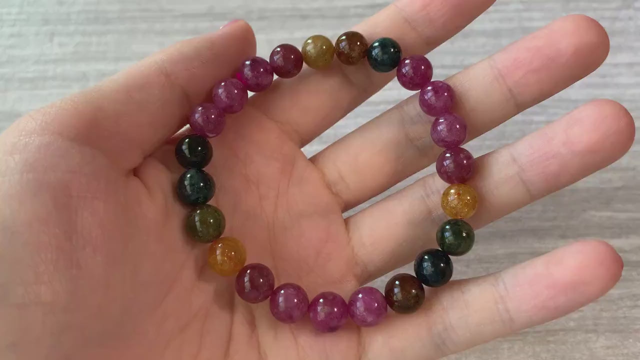 Video of an elastic natural tourmaline bead bracelet with multicolor yellow, green, pink, and red 8 mm stones