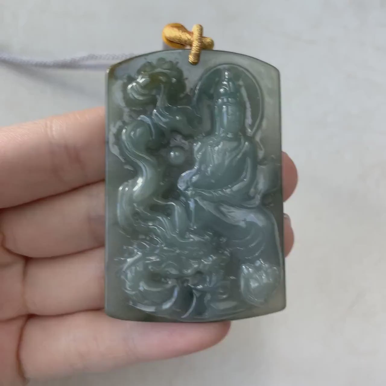 Video of a hand-carved natural jade pendant with Guan Yin and dragon, intricate detailed design, green and elegant