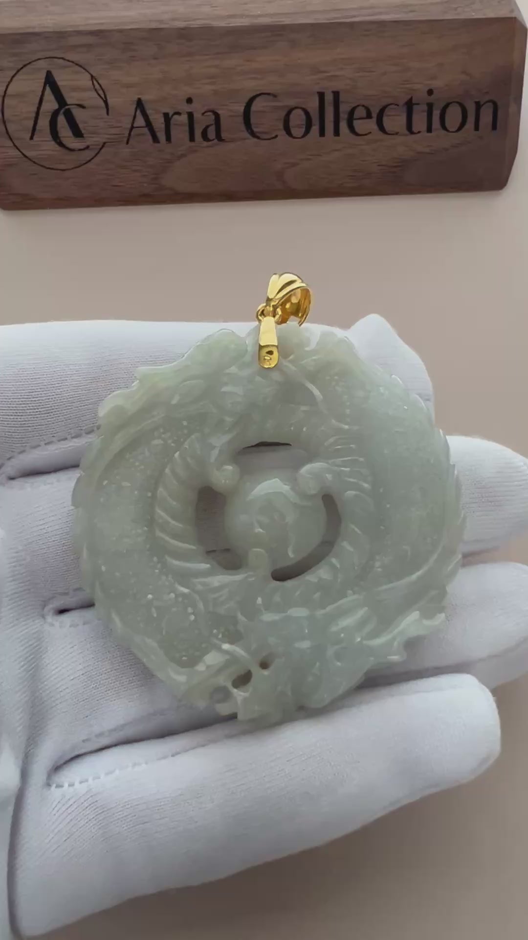 Video of a luminous green jade twin-dragon pendant with 18K gold bail, carved in a bold circular style