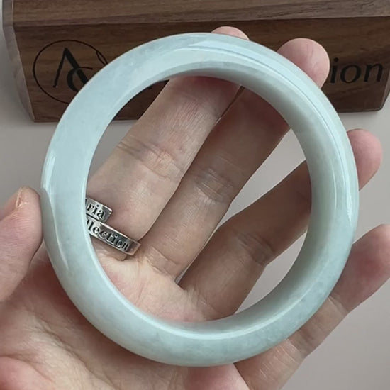 Video of an icy light blue Burmese jadeite bangle with soft mottling, rounded profile, and high-polish finish