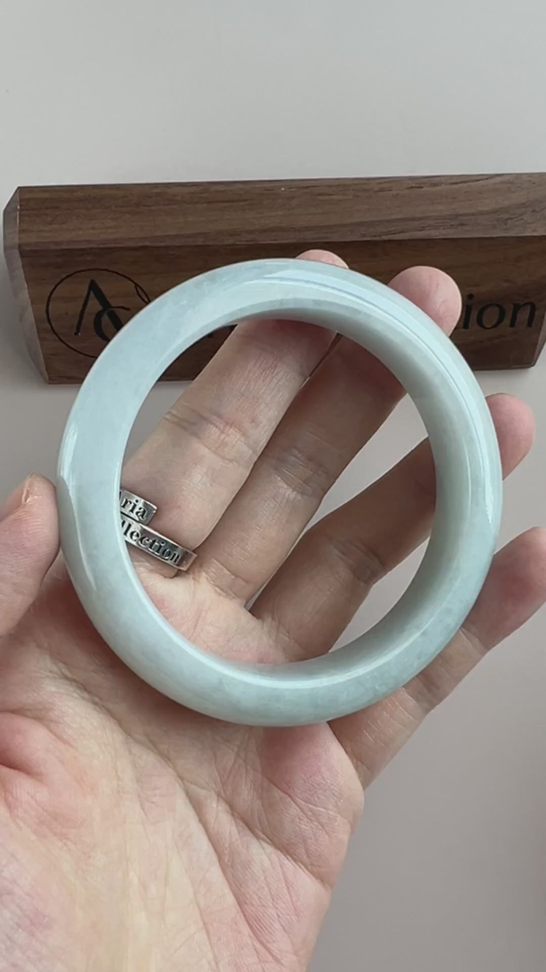 Video of an icy light blue Burmese jadeite bangle with soft mottling, rounded profile, and high-polish finish