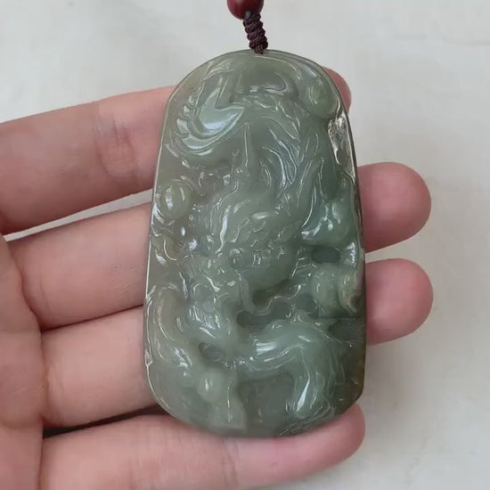 Video of hand-carved olive green jadeite dragon pendant with intricate carved scales, claws, and tail.