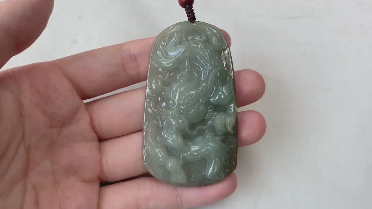 Video of hand-carved olive green jadeite dragon pendant with intricate carved scales, claws, and tail.