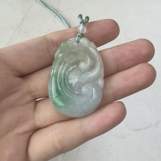 Video of a hand-carved jadeite jade Ruyi pendant in white and vibrant green with a soft natural glow