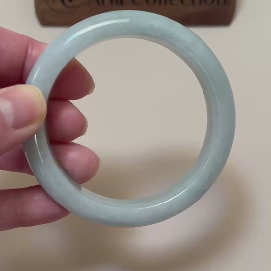 Video of a light blue Burmese jadeite bangle with cloudy variations, rounded profile, and high-polish finish