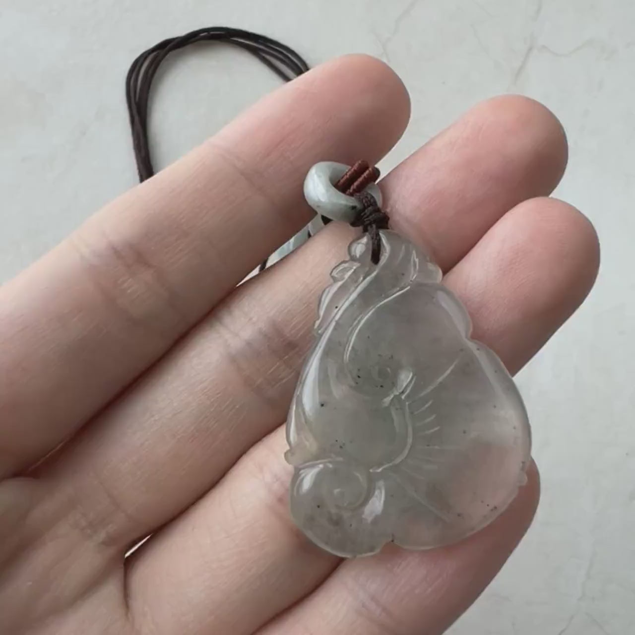 Video of a translucent grey-green jadeite pendant with carved money coin and Ruyi design, elegant and luminous