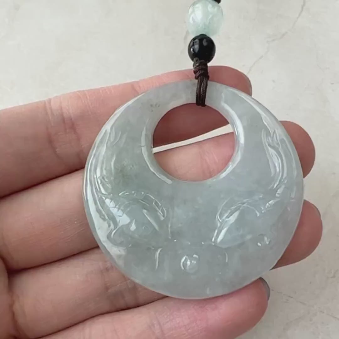 Video of a hand-carved pale green and creamy gray jade pendant with two fish in a circular openwork design