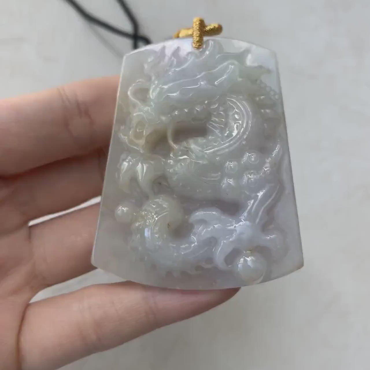 Video of a hand-carved natural jadeite dragon pendant in soft semi-translucent purple-gray jade with intricate details