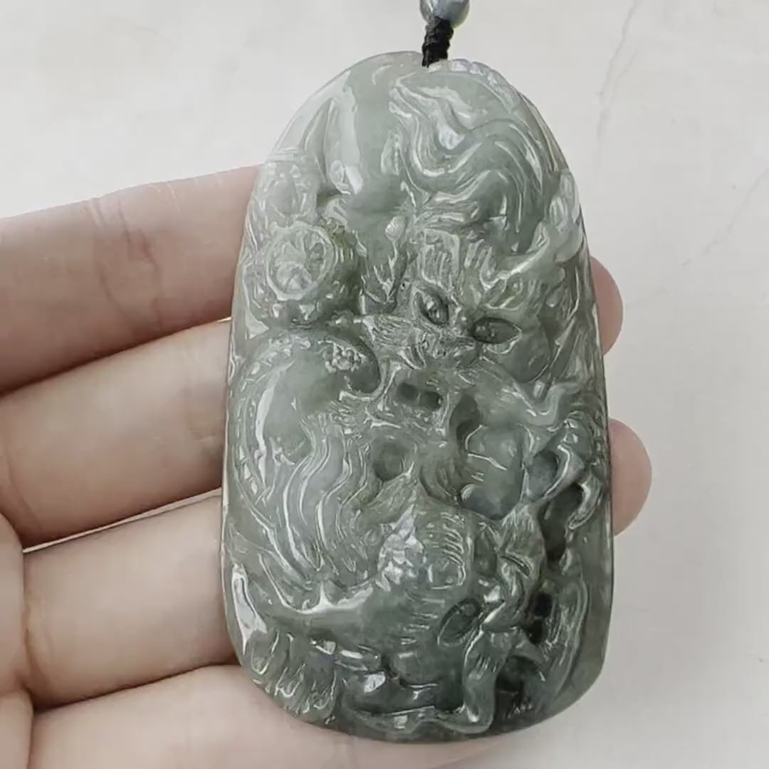 Video of a hand-carved green jade twin dragon pendant with intricate scales, claws, and flowing tails