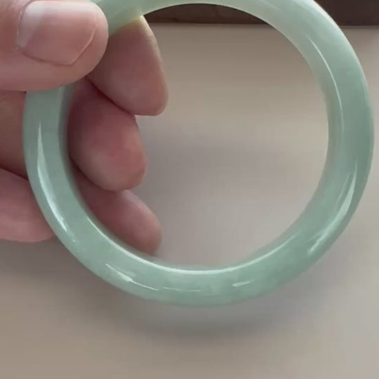 Video of a polished Burmese Type A jadeite bangle in soft light green-blue with carved grooves and subtle translucency