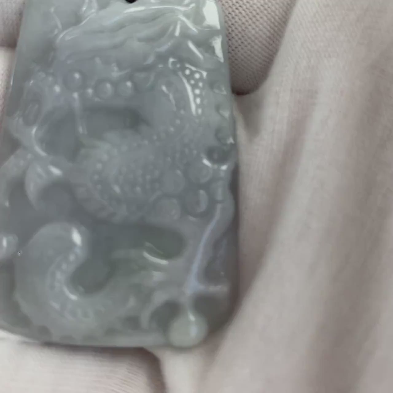 Video of a hand-carved gray jadeite dragon pendant with glowing semi-translucent stone and decorative bead necklace