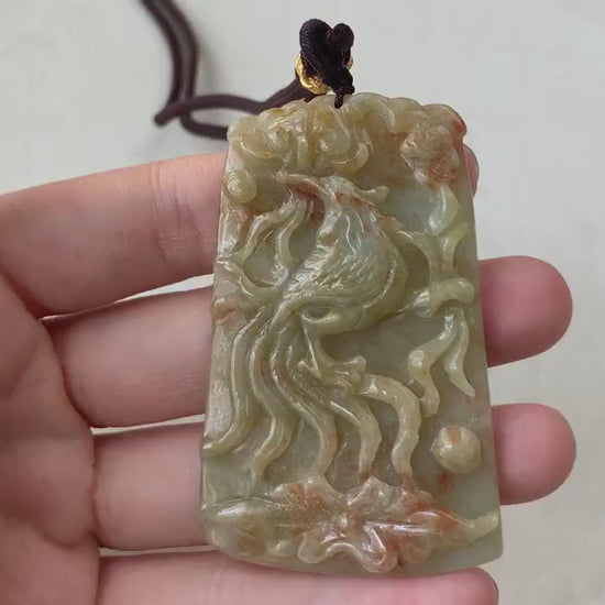 Video of a hand-carved jadeite jade phoenix pendant in red and yellow hues with intricate feather details