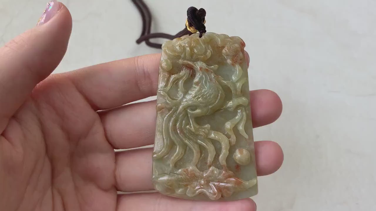 Video of a hand-carved jadeite jade phoenix pendant in red and yellow hues with intricate feather details