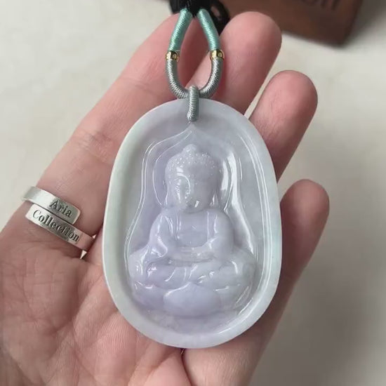 Video of hand-carved pendant with serene Baby Buddha on lotus, intricate details, symbolic and elegant style