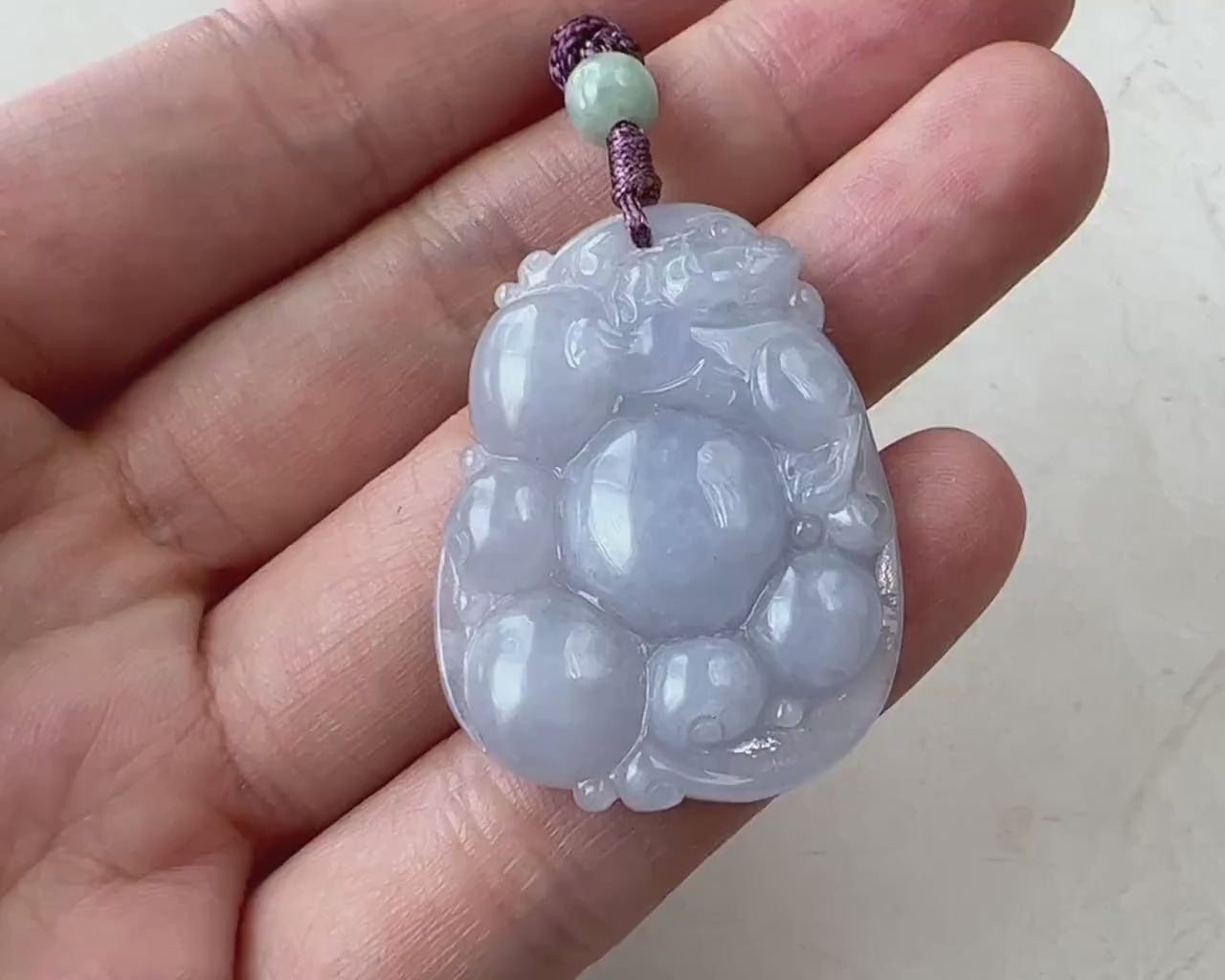 Video of a finely carved purple semi-translucent jade Pi Xiu with a luminous glow and abstract dragon-lion form
