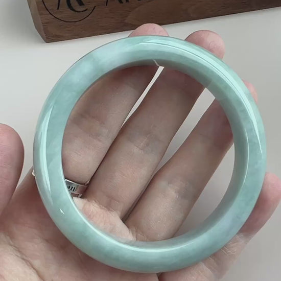 Video of a classic Burmese Type A jadeite bangle in light green-blue with a polished, semi-translucent rounded form