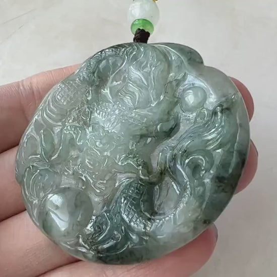 Video of a hand-carved translucent jade dragon pendant with detailed scales, claws, tail, and expressive face