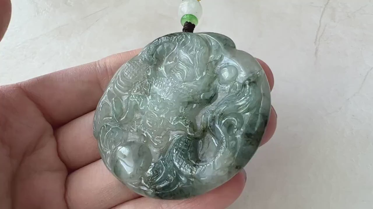 Video of a hand-carved translucent jade dragon pendant with detailed scales, claws, tail, and expressive face