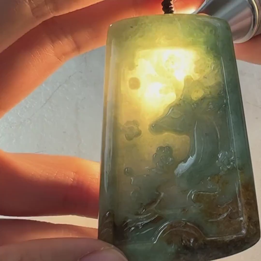 Video of a one-of-a-kind jade pendant with hand-carved deer, green tones, red and yellow accents, and mountain motifs