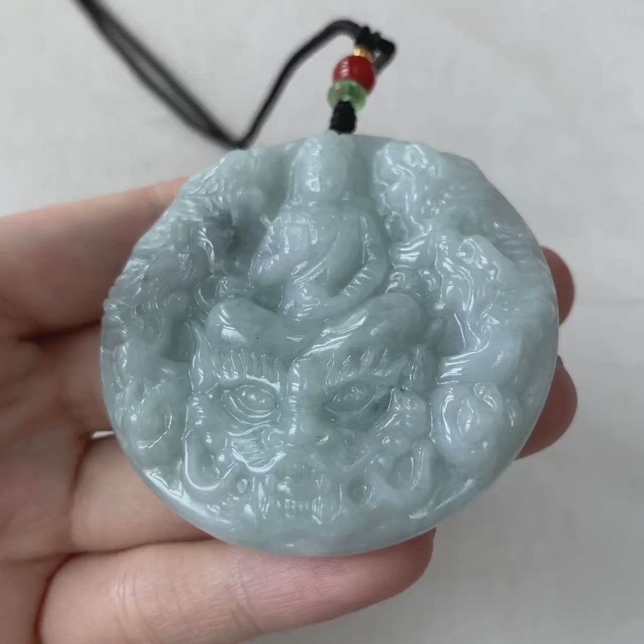 Video of a hand-carved jade pendant with Guan Yin and nine dragons, intricate green spiritual jewelry piece