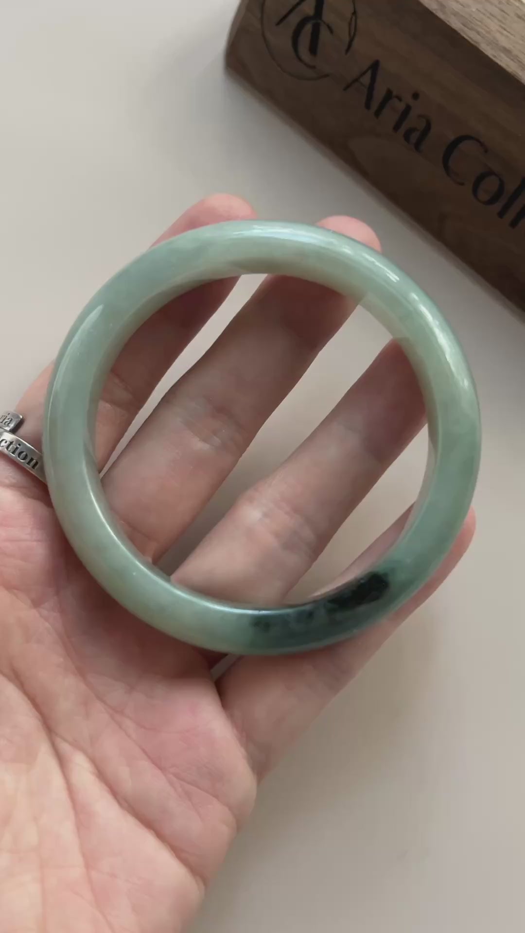 Video of a polished light green Burmese jadeite bangle with deep green-black natural color concentration and soft translucenc