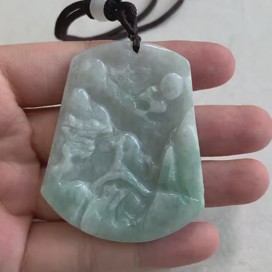Video of hand-carved green jade pendant with serene mountain forest landscape, bridge, and tiny houses