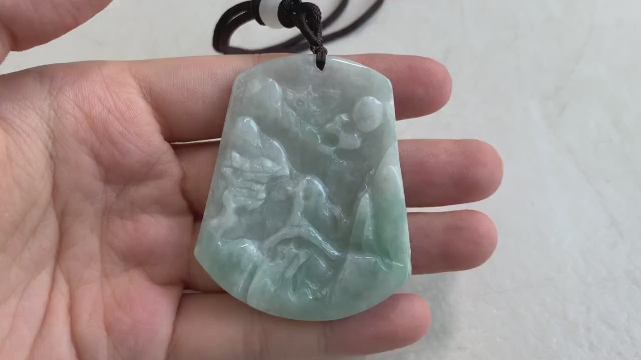 Video of hand-carved green jade pendant with serene mountain forest landscape, bridge, and tiny houses