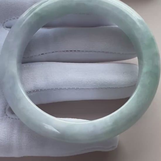 Video of a classic Burmese Type A jadeite bangle in icy light green with gray marbling and a high-polish rounded finish