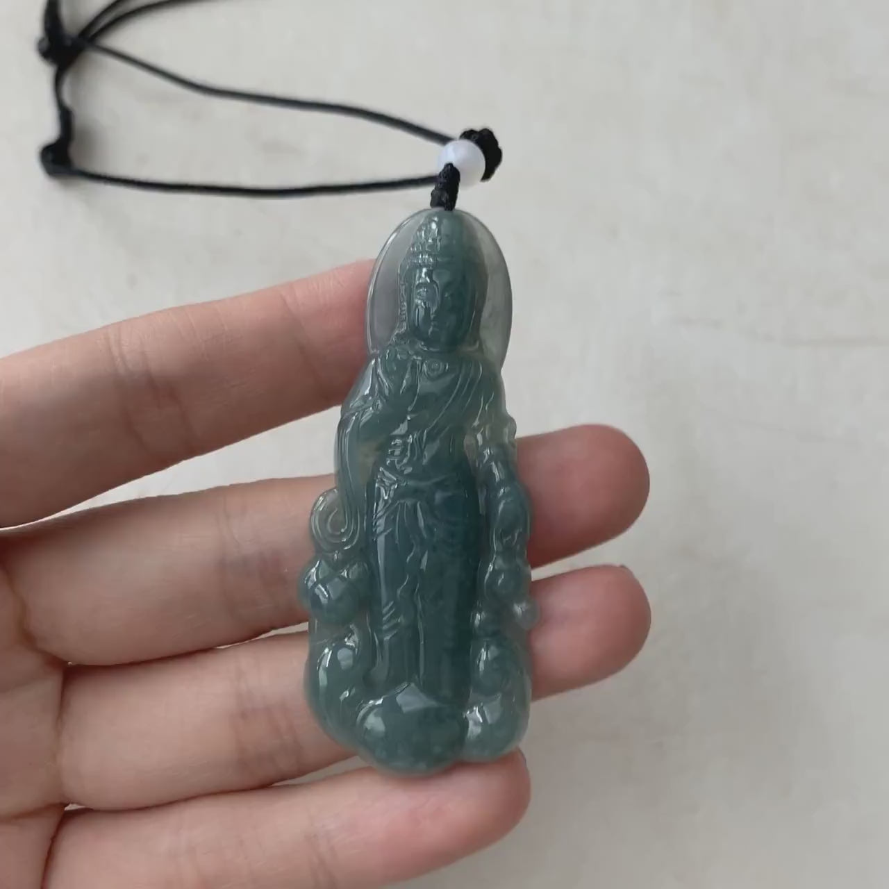 Video of a one-of-a-kind green jade Guan Yin pendant with intricate hand-carved dual-sided detailing