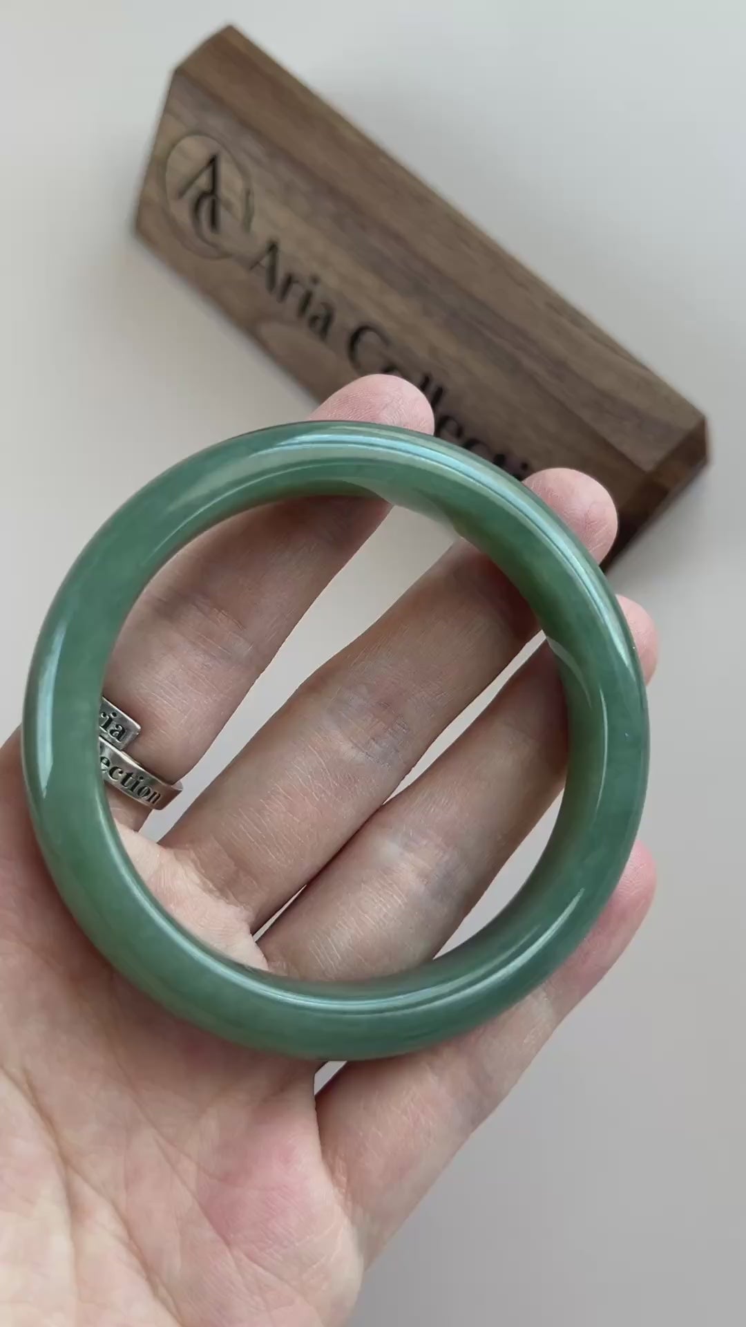 Video of a classic Burmese Type A jadeite bangle in rich green with mottled texture, polished rounded profile, and soft trans