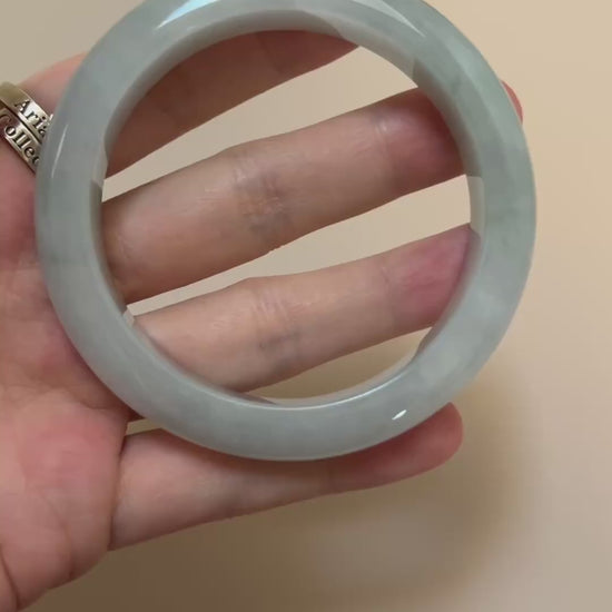 Video of an icy light green-blue Burmese jadeite bangle with smooth rounded form, soft mottling, and polished finish