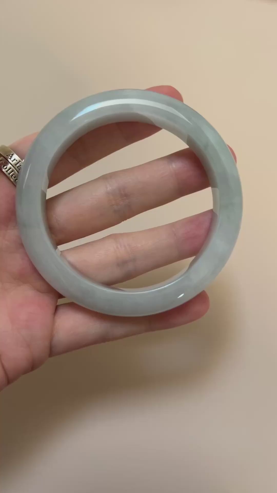 Video of an icy light green-blue Burmese jadeite bangle with smooth rounded form, soft mottling, and polished finish